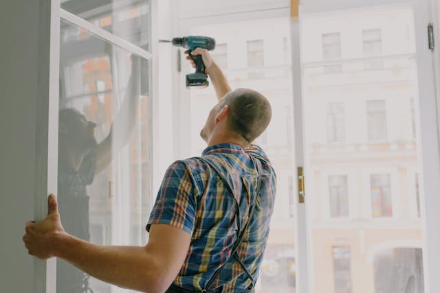 person working on a window with a drill